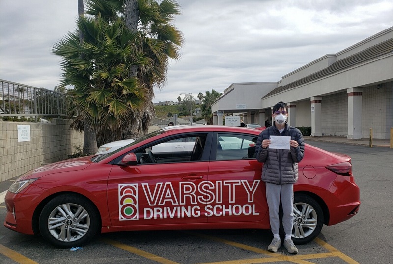 Laguna Niguel Driving School Young Man Standing Next to a Training Vehicle at the DMV