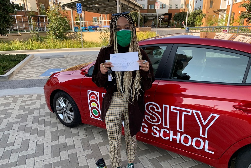 Driving Lessons in Laguna Female Student Standing Next to a Red Training Vehicle