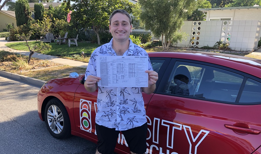 Driving Lessons in Laguna Male Student Standing Next to a Red Training Vehicle