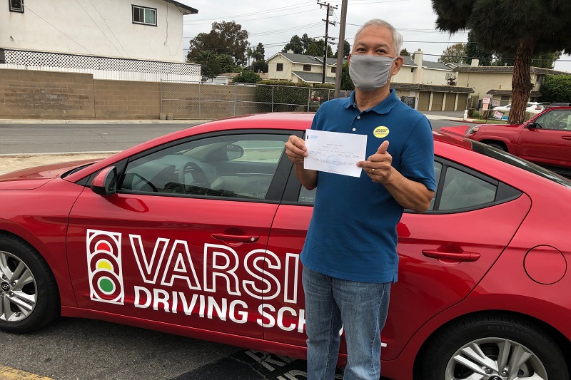 Best Place to Take your Drivers ed Test in Newport Beach Adult Male Standing Next to a Training Vehicle with a Passed Test in Hand