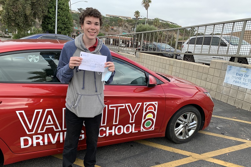 Can a 17 Year Old Drive with Passengers in California Male Teen Standing Next to a Training Vehicle Holding Up His Permit