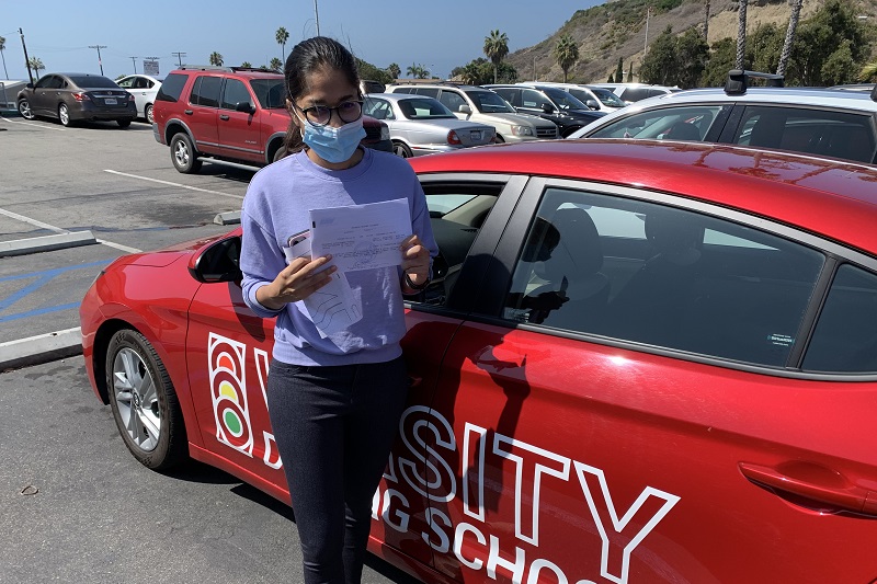 Can a 17 Year Old Drive with Passengers in California Female Student Standing Next to a Training Vehicle Holding Up Her Permit