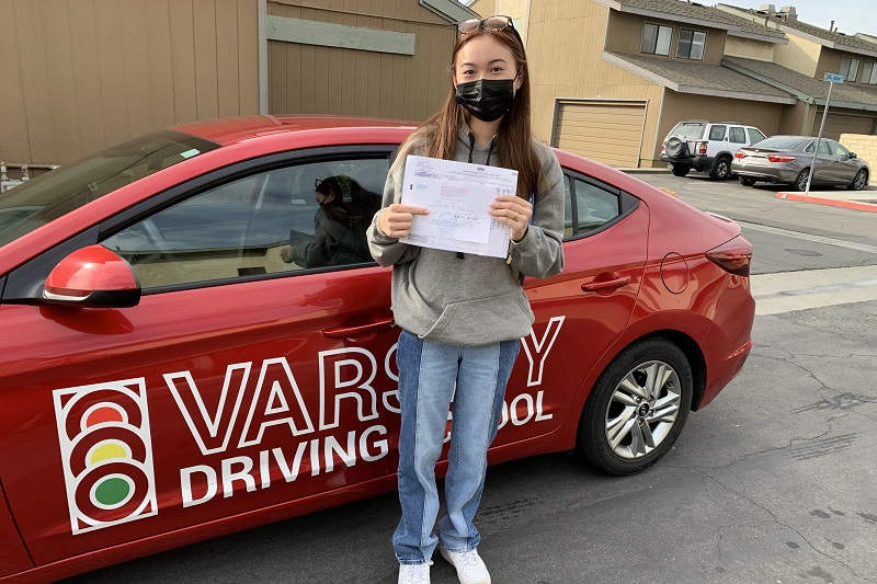 Fountain Valley High School Driving School Female Student Standing Next to a Training Vehicle