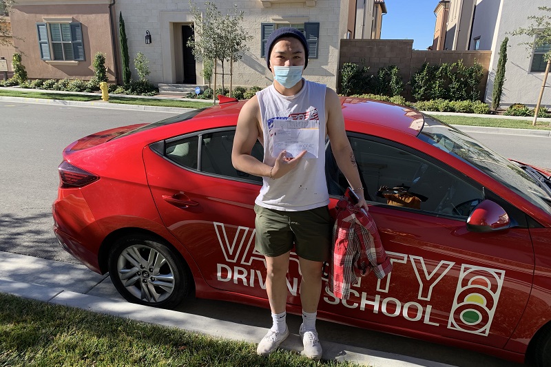 Huntington Beach High School Driving School Male Student Standing Next to a Training Vehicle