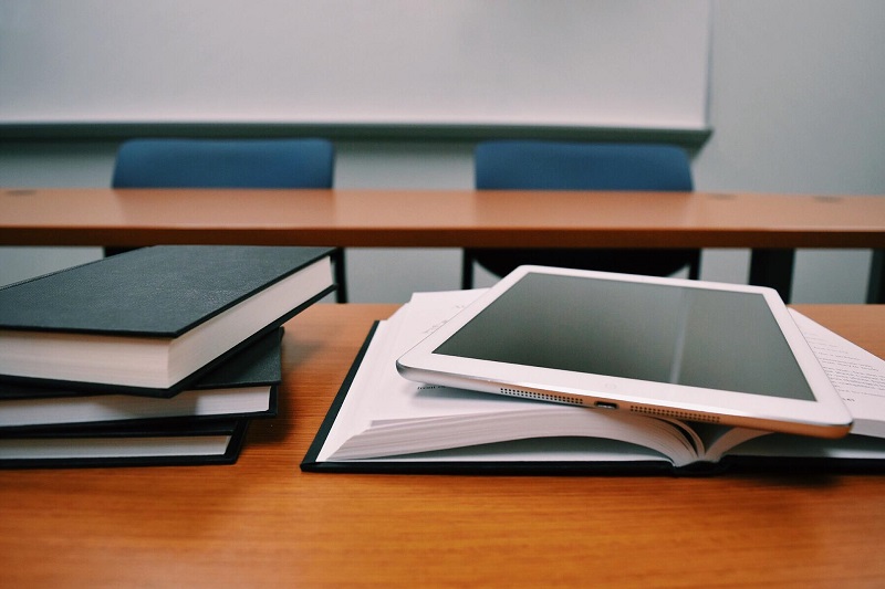 Huntington Beach High School Reviews Close Up of an Empty Desk with an Open Book and a Tablet