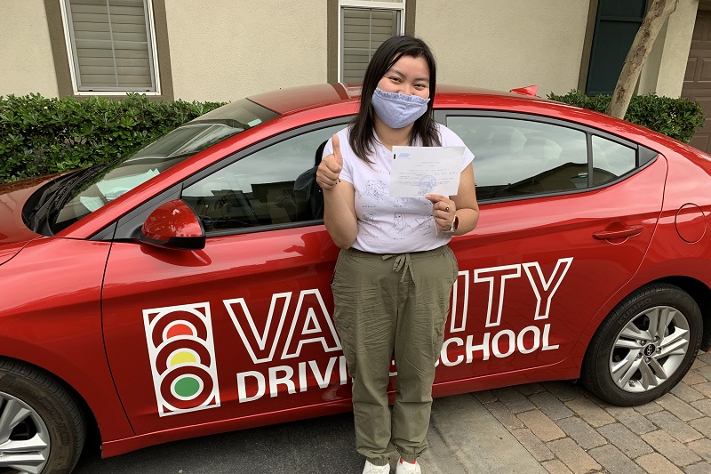 What is the Fee for Driving School in Orange County Female Student Standing Next to a Training Vehicle