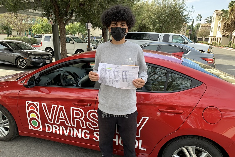 What is the Fee for Driving School in Orange County Male Student Standing Next to a Training Vehicle