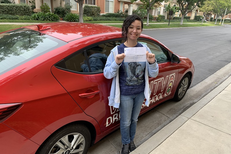 Places to Practice Driving in Tustin Female Student Standing Next to a Training Vehicle