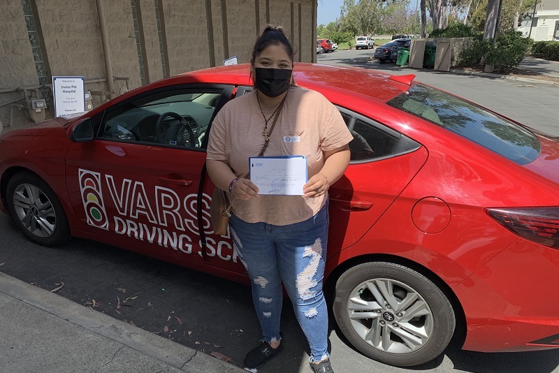 Where to Take your Santa Ana Driving Lessons Student Standing Next to a Training Vehicle Outside of a DMV