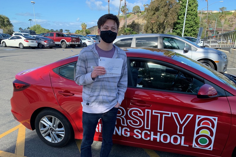 Best Estancia High School Driving School Student Standing Next to a Training Vehicle in a Parking Lot