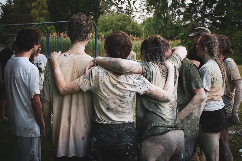 Teen Drivers and Passengers a Group of Teens Dirty with Mud Standing Together With Their Arms Over Each Other