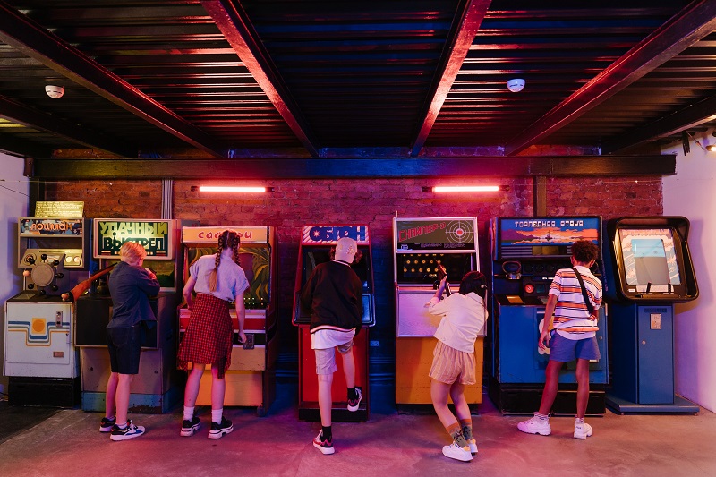 Teen Drivers and Passengers a Group of Teens Playing Arcade Games in a Dimly Lit Arcade