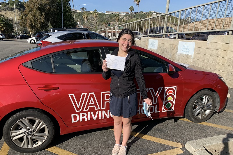 Hillview High School Driving School Student Standing Next to a Training Vehicle in a Parking Lot