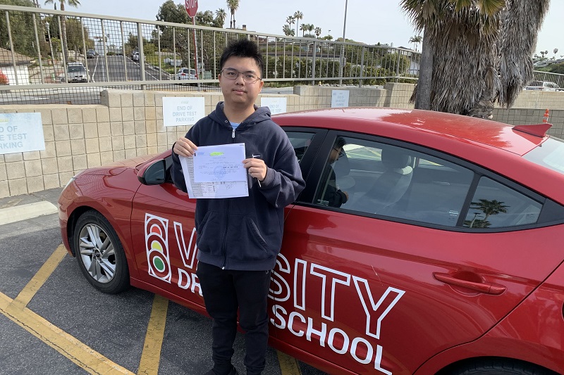 Aliso Niguel High School Drivers Ed Student Standing Next to a Training Vehicle in a DMV Parking Lot