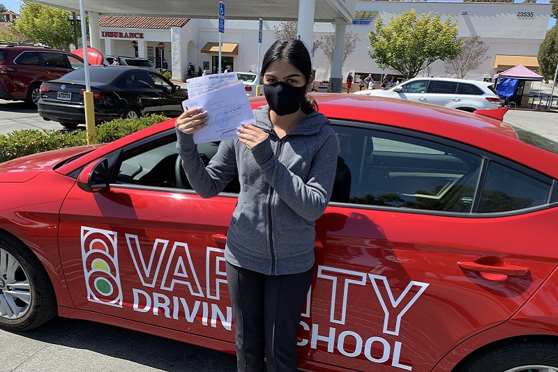 Aliso Niguel High School Driving School Student Standing Next to a Training Vehicle in a DMV Parking Lot