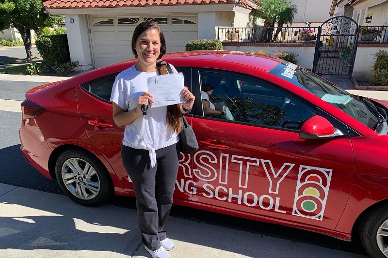 Best Acaciawood High School Driving School Student Standing Next to a Training Vehicle in Front of a Home