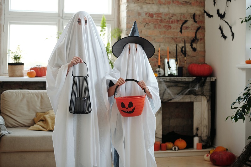 Halloween Safe Driving Tips Two Kids Dressed Up as Ghosts Holding Trick or Treat Bags