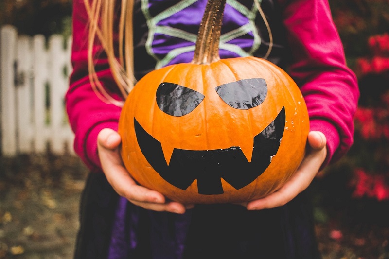 Halloween Safe Driving Tips Close Up of a Young Girl Holding a Painted Pumpkin