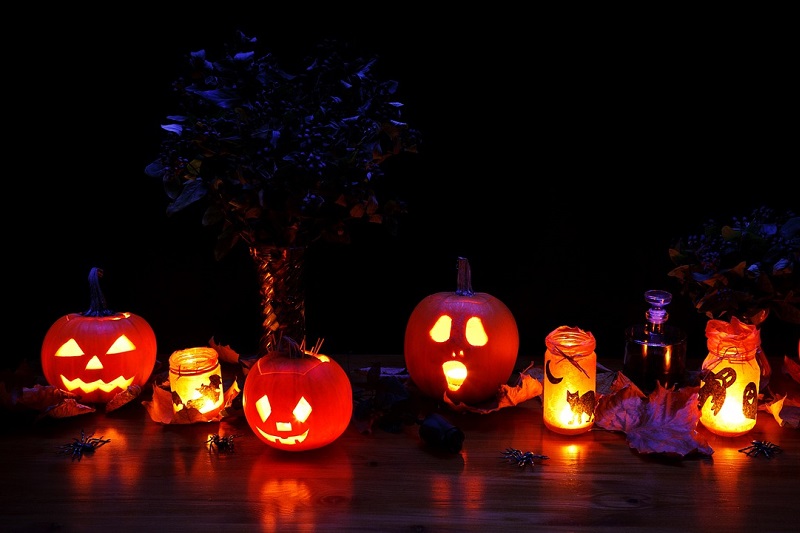 Halloween Safe Driving Tips Three Jack O Lanterns Lit Up at Night with a Few Lit Candles Around Them