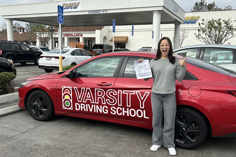 Best Katella High School Behind the Wheel Training Student Standing Next to a Training Vehicle in a DMV Parking Lot