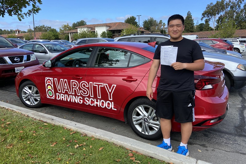 Best Katella High School Driving School Student Standing Next to a Training Vehicle in a Parking Lot