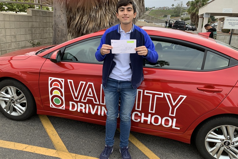 Best Canyon High School Behind the Wheel Training Student Standing Next to a Training Vehicle in a DMV Parking Lot