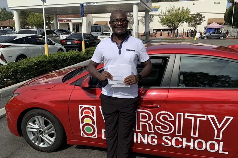 Which Adult Driving School is Best in Irvine Adult Standing Next to a Training Vehicle in a Parking Lot