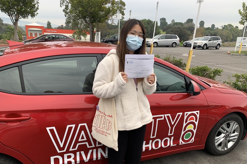 Best Heritage High School Behind the Wheel Training Student Next to a Training Vehicle in a Public Parking Lot