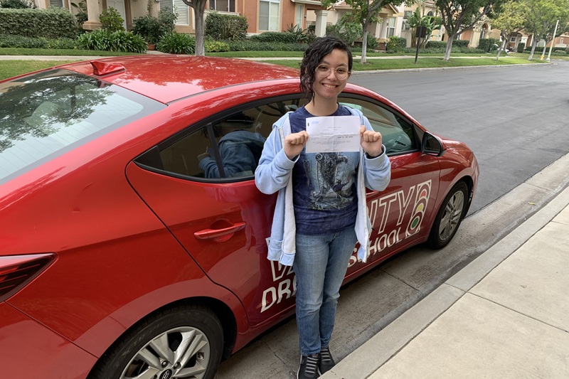 Best John F. Kennedy High School Driving School Student Standing Next to a Training Vehicle on a Street
