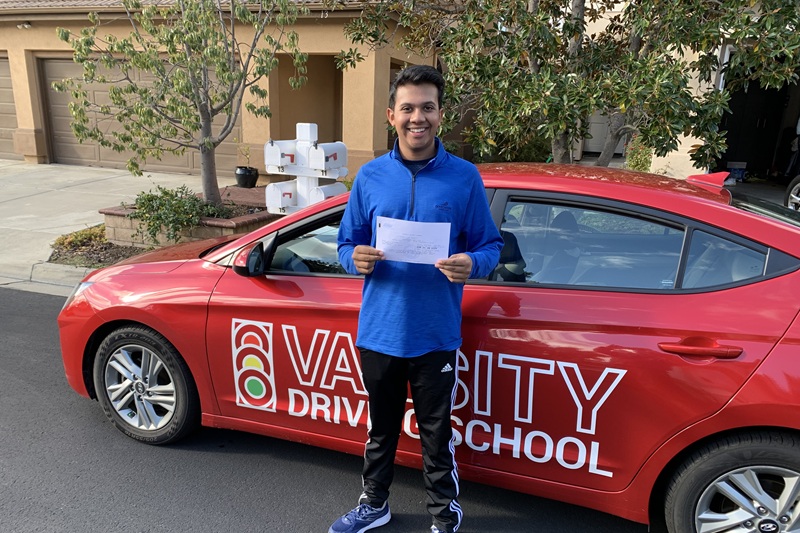 Best Godinez Fundamental High School Behind the Wheel Training Student Standing Next to a Training Vehicle Parked Outside a Home